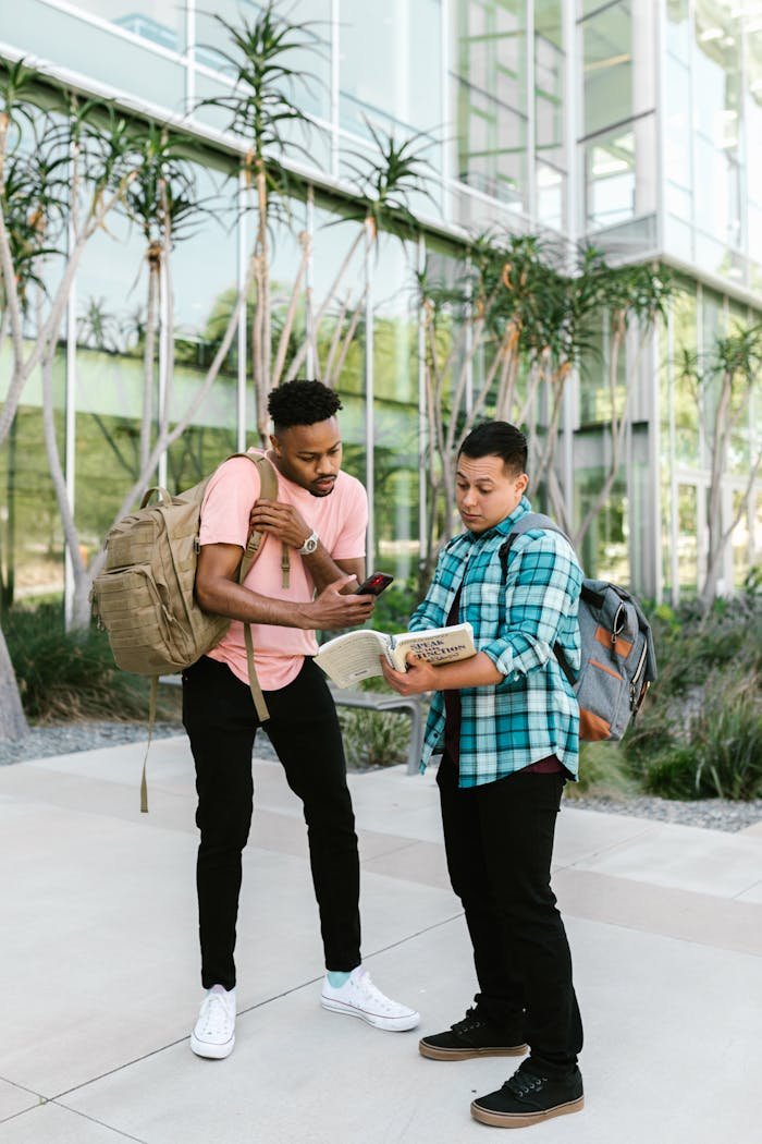 why-choose-us Two students with backpacks discuss study material on a sunny campus day, standing outdoors.