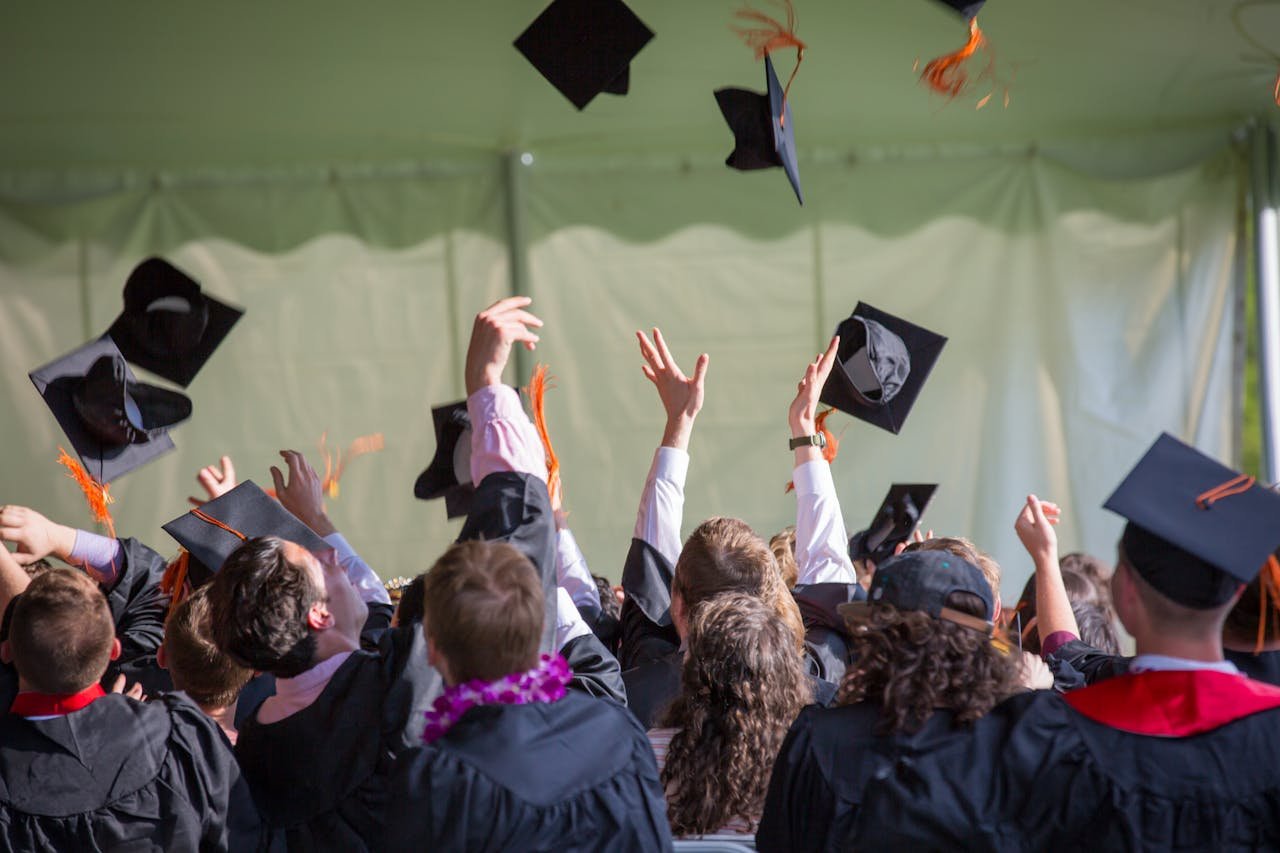 portfolio-05 Group of graduates celebrating by tossing caps into the air during a graduation ceremony.
